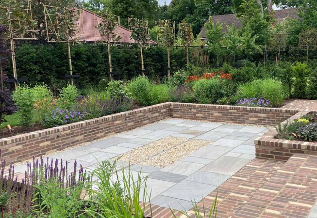 Warm brick walling, surrounded by vibrant planting and lush evergreen boundaries